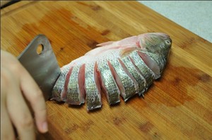將鱸魚(yú)清洗干凈，從脊椎處切斷至腹部，腹部保留1cm左右不要切斷。