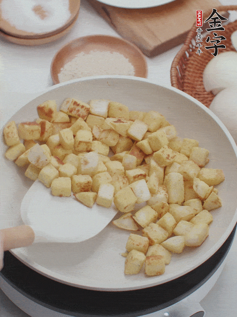 起鍋熱油，倒入饅頭丁，小火煎至蛋液凝固定型再翻面，饅頭丁部煎至金黃時(shí)盛起待用。
