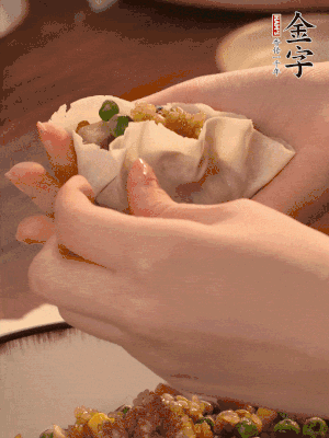 取一大勺餡料放進(jìn)餃子皮里，用大拇指按住頂部餡料，再用虎口掐出形狀。