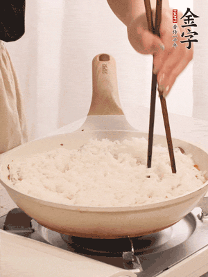 把瀝干水分的米飯均勻鋪在上面，筷子戳幾個(gè)洞，以便透氣，轉(zhuǎn)小火蓋上蓋子燜至水分收干，大概10分鐘。